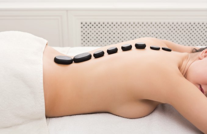 Woman getting hot stones massage at spa salon